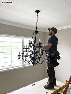 a man is working on a chandelier in the middle of an unfinished room