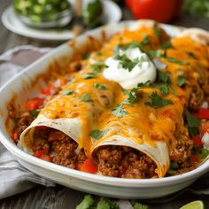 an enchilada dish with meat, cheese and sour cream on the top