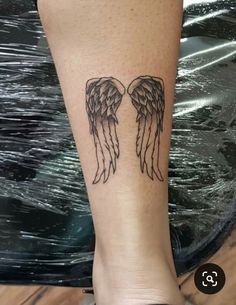 a woman's leg with an angel wing tattoo on it