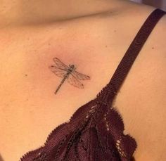 a woman's chest with a small tattoo of a dragonfly on her left shoulder