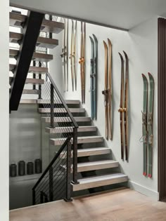 there are many skis hanging on the wall next to the stairs in this house