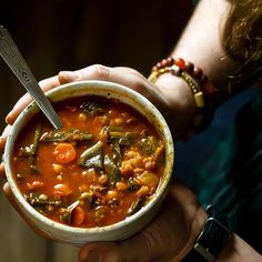 a person holding a bowl of soup in their hands