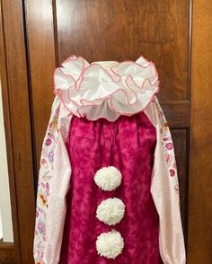 a pink dress with white pom poms hanging from it's back door