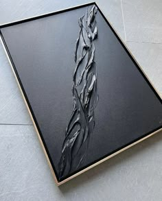 a black and gold framed art piece on the floor