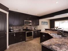 a kitchen with granite counter tops and stainless steel appliances, along with dark wood cabinets