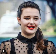 a close up of a person wearing a black shirt with polka dots and red lipstick