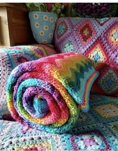 there is a crocheted blanket and pillows on the bed