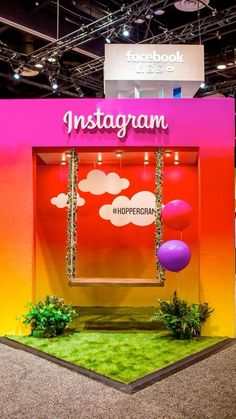 an exhibit booth with fake grass and balloons in front of the entrance to instagramm