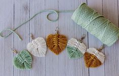 three tasseled heart shaped earrings sitting next to a spool of thread on a white wooden surface