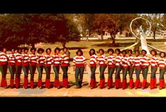 a group of women in red and white shirts standing next to each other near a statue