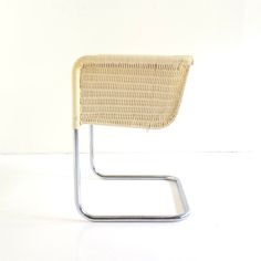 a white chair with a metal frame and wicker backrest on a white background