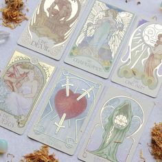 four tarot cards with angels on them sitting next to some dried flowers and stones