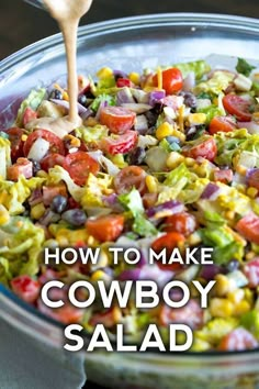 a salad in a glass bowl with a wooden spoon and dressing being poured into it