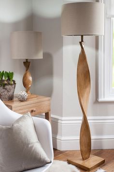 a living room filled with furniture and a lamp on top of a hard wood floor