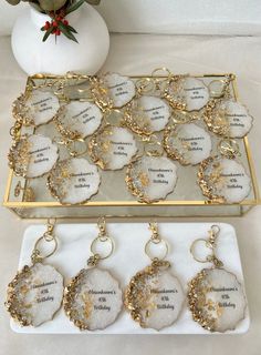 two trays filled with white and gold earrings on top of a table next to a vase