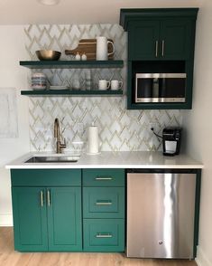 a kitchen with green cabinets and stainless steel appliances