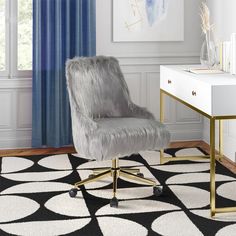 a gray chair sitting on top of a black and white rug next to a desk