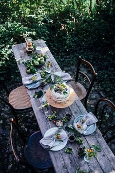 the table is set with plates and bowls on it for an outdoor dinner party or gathering