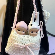 two little rabbits are sitting in a crocheted purse