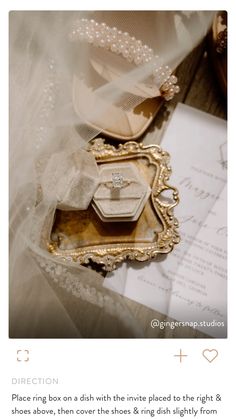 an image of wedding rings in a box with pearls and lace on it, surrounded by other items