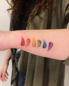 a woman's arm with different colored lipstick swatches on the left forearm and right arm