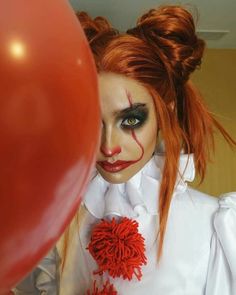 a woman with red hair and makeup holding a balloon