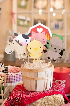 there are many farm animals on sticks in the basket and cake toppers with straws