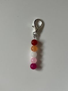 a keychain with three different colored beads hanging from it's side on a white surface