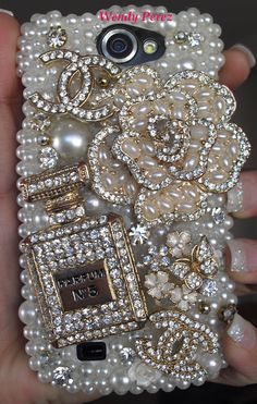 a person is holding a cell phone with pearls and jewels on it's back