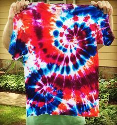 a man holding up a red, white and blue tie - dyed t - shirt