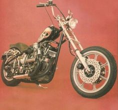 a black and silver motorcycle parked in front of a red wall with a skull on the back tire