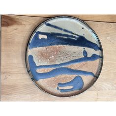 a blue and white plate sitting on top of a wooden table next to a wall