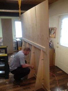 a man kneeling down on the floor next to a piece of wood that is being worked on