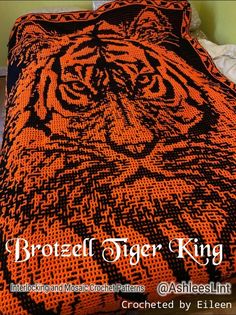 an orange and black crocheted tiger blanket on a bed with the words, brother tiger king written across it