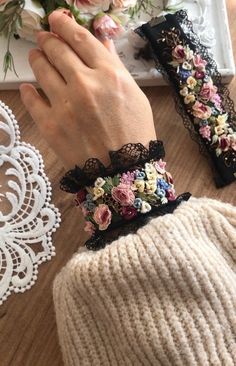 the woman is wearing two bracelets with flowers on them and lace around her wrist