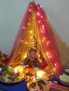 a table topped with plates and bowls filled with food next to a tent covered in lights