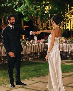 a man in a suit and tie standing next to a woman in a white dress