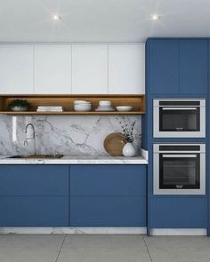 a kitchen with blue cabinets and marble counter tops, along with an oven in the center