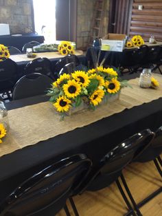 the table is set with sunflowers and black chairs