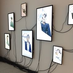 a wall with many framed pictures and wires attached to the wall, all connected together