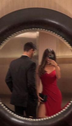 a woman in a red dress standing next to a man