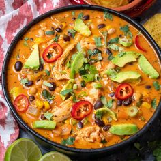 a bowl of chicken tortilla soup with black beans, avocado and cilantro