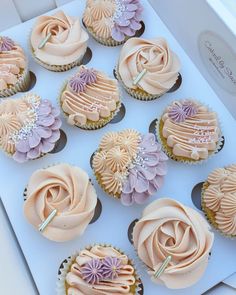 twelve cupcakes with pink frosting and purple flowers