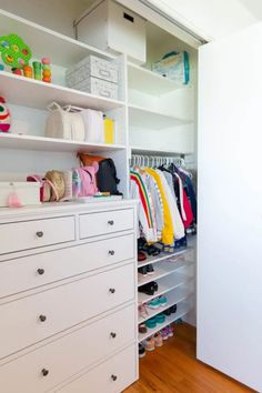 a white closet with lots of clothes and shoes on shelves next to a wooden floor