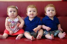 three children sitting on a red couch with their hands in their pockets and looking at the camera