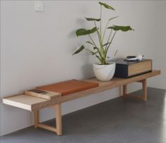 a potted plant sitting on top of a wooden bench next to a book shelf