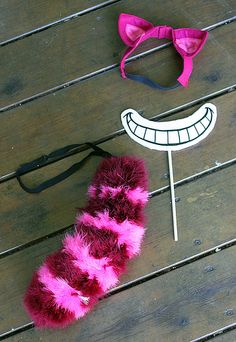 a pair of pink and black hair ties next to a fake smile face on a wooden floor