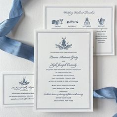 the wedding stationery is laid out on top of each other with blue satin ribbons