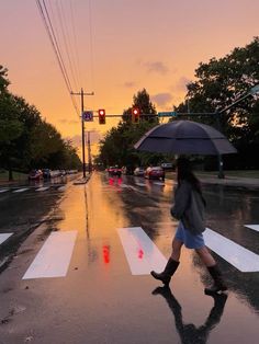 a woman with an umbrella crosses the street at sunset on a rainy day in washington, d c