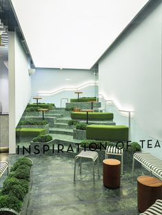 an indoor area with benches, tables and plants on the ground in front of stairs